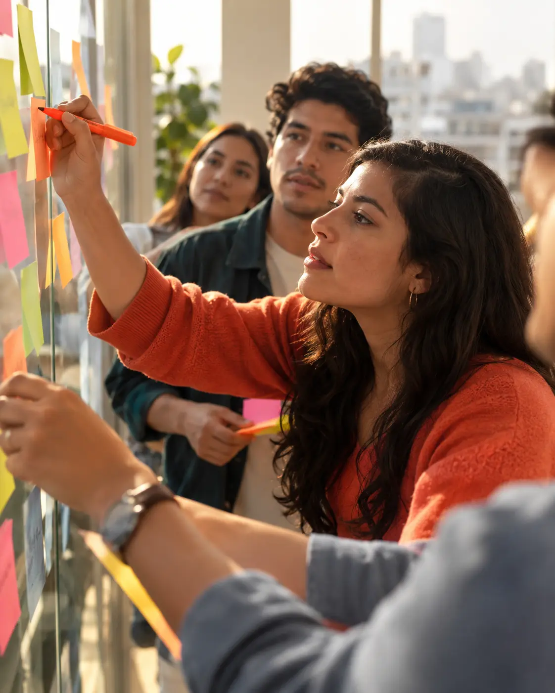 Equipo pegando notas adhesivas en una pared de vidrio durante una lluvia de ideas